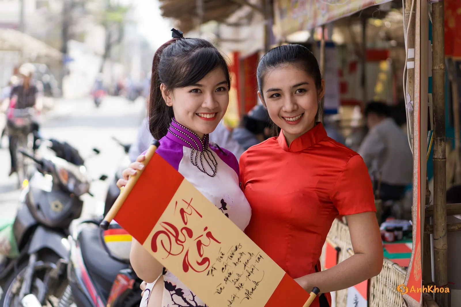 Ao dai e calligrafia durante il Tết Due giovani donne vietnamite in ao dai viola e rosso con rotolo di calligrafia durante le feste del Tết a Ho Chi Minh City