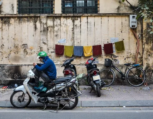 Autista GrabBike con casco verde che controlla lo smartphone in strada