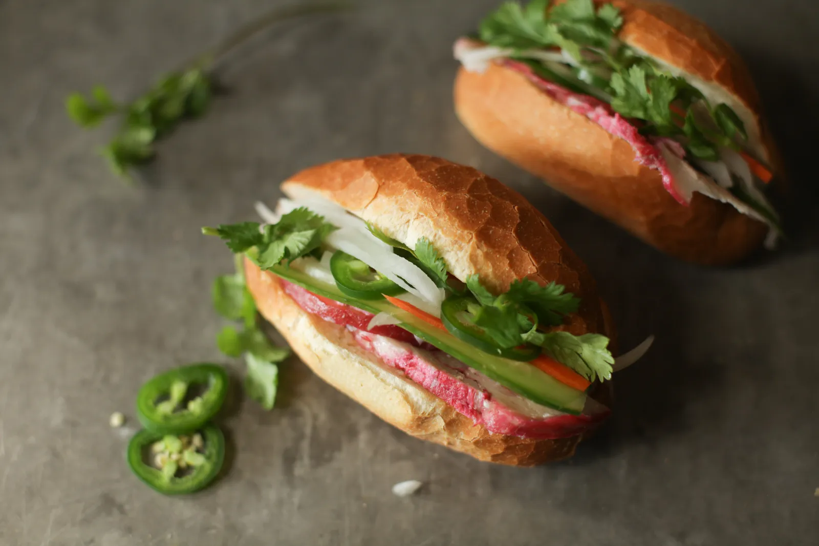 Due mini banh mi vietnamiti farciti con salumi, verdure marinate, peperoncino fresco e coriandolo, gli ingredienti classici del panino