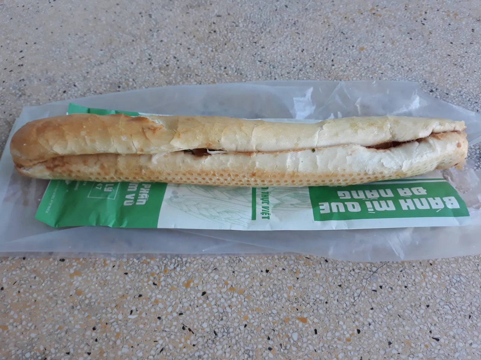 Banh mi que di Hai Phong, la baguette sottile e croccante con paté e salsa piccante servita nella busta di carta