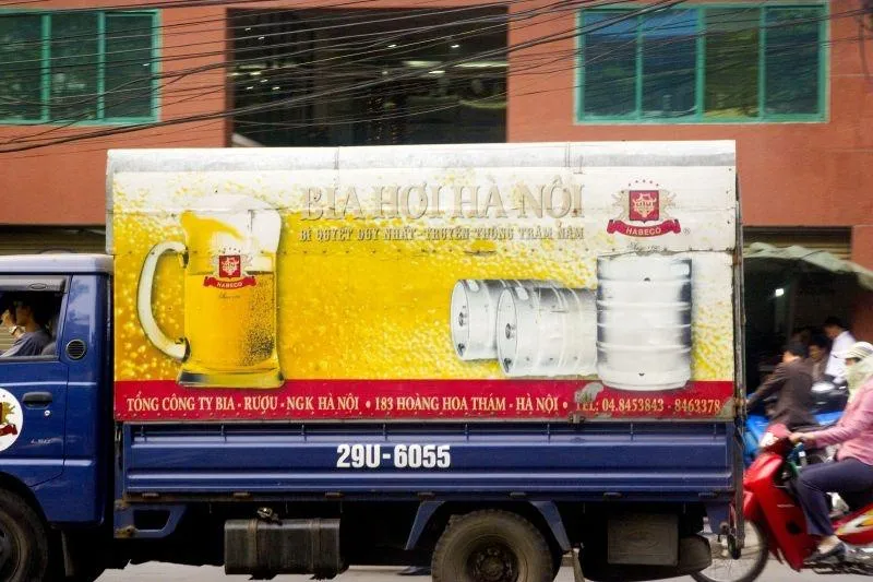 Un camion della birreria Bia Hoi Hanoi attraversa la città con il murale pubblicitario della birra e dei fusti dipinti sulla fiancata