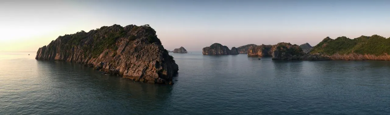 Panorama della baia di Lan Ha al tramonto con le isolette calcaree nel mare calmo
