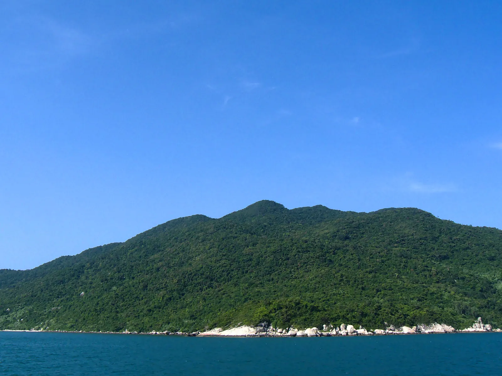 Panorama del parco marino di Cham Island con barche da pesca lungo la costa rocciosa