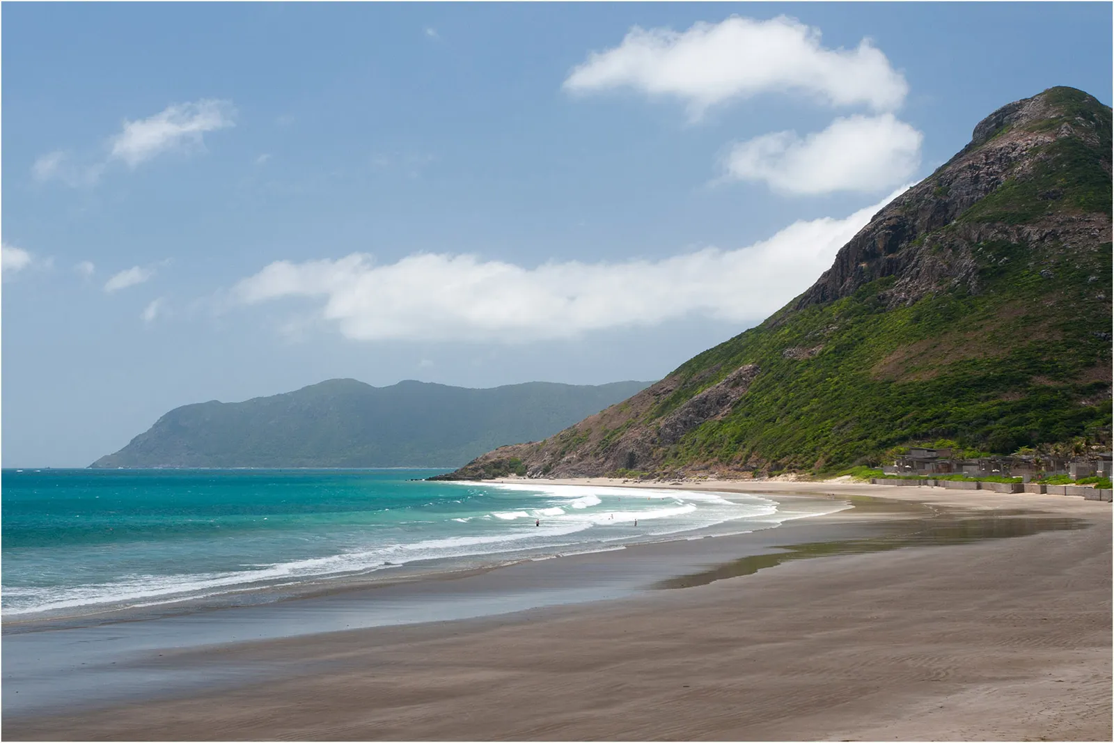 La spiaggia di Dat Doc a Con Dao La spiaggia selvaggia di Dat Doc a Con Dao con mare turchese e colline verdi