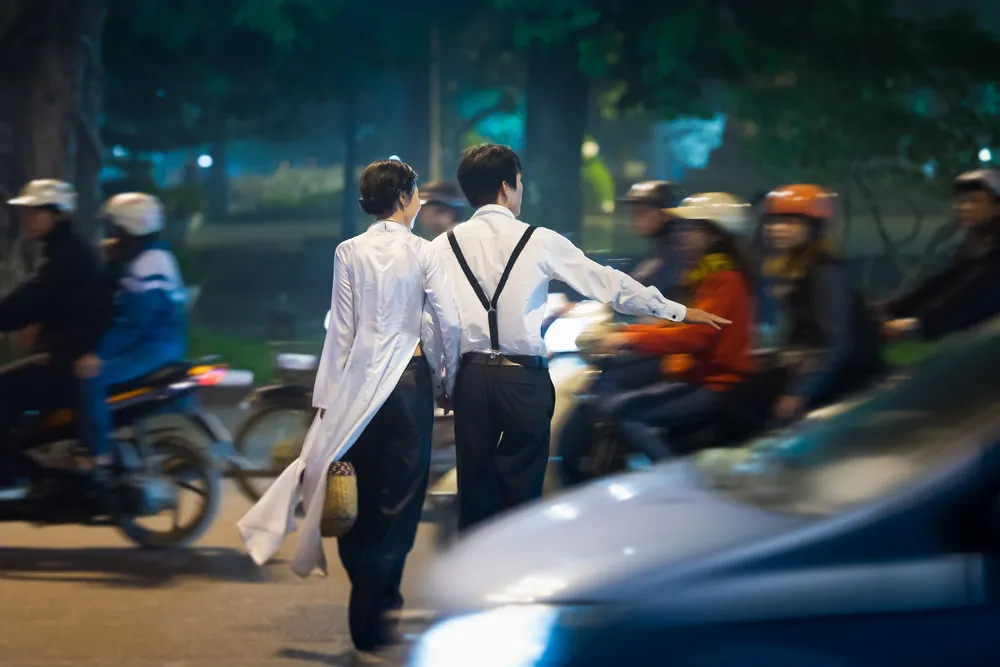 Coppia attraversa la strada nel traffico vietnamita