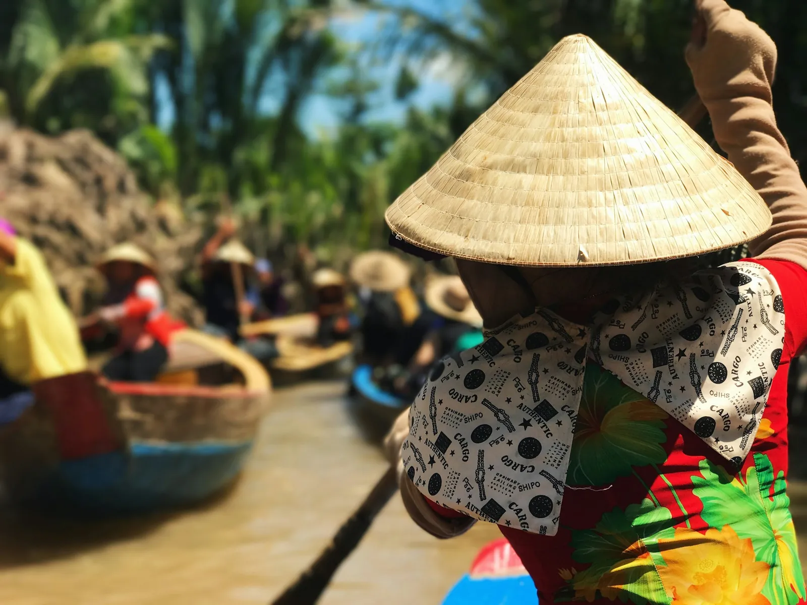 Rematore con il tipico copricapo a cono lungo un canale del Delta del Mekong