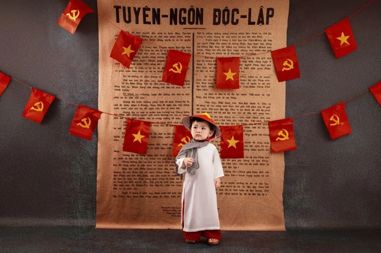 Bambino in abiti tradizionali davanti alla Dichiarazione d'indipendenza del Vietnam Bambino in abiti tradizionali vietnamiti davanti a una riproduzione della Dichiarazione d'indipendenza del Vietnam