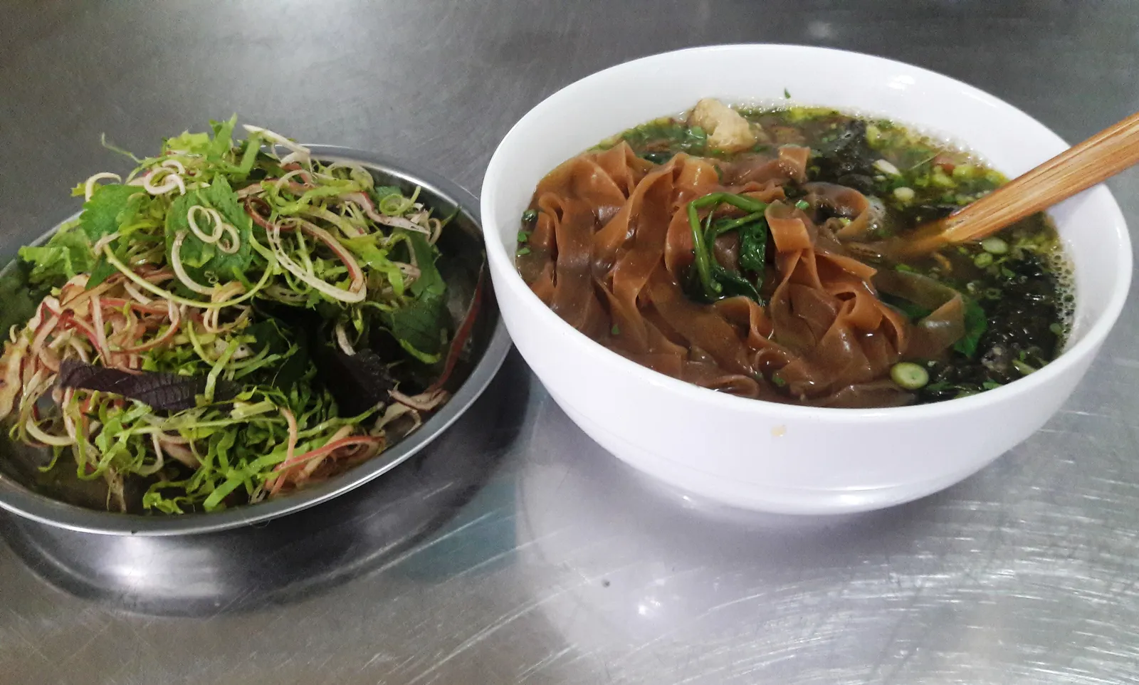 Banh da cua, il piatto simbolo di Hai Phong Banh da cua, la zuppa di pasta di riso rossa al granchio tipica di Hai Phong, servita con verdure fresche