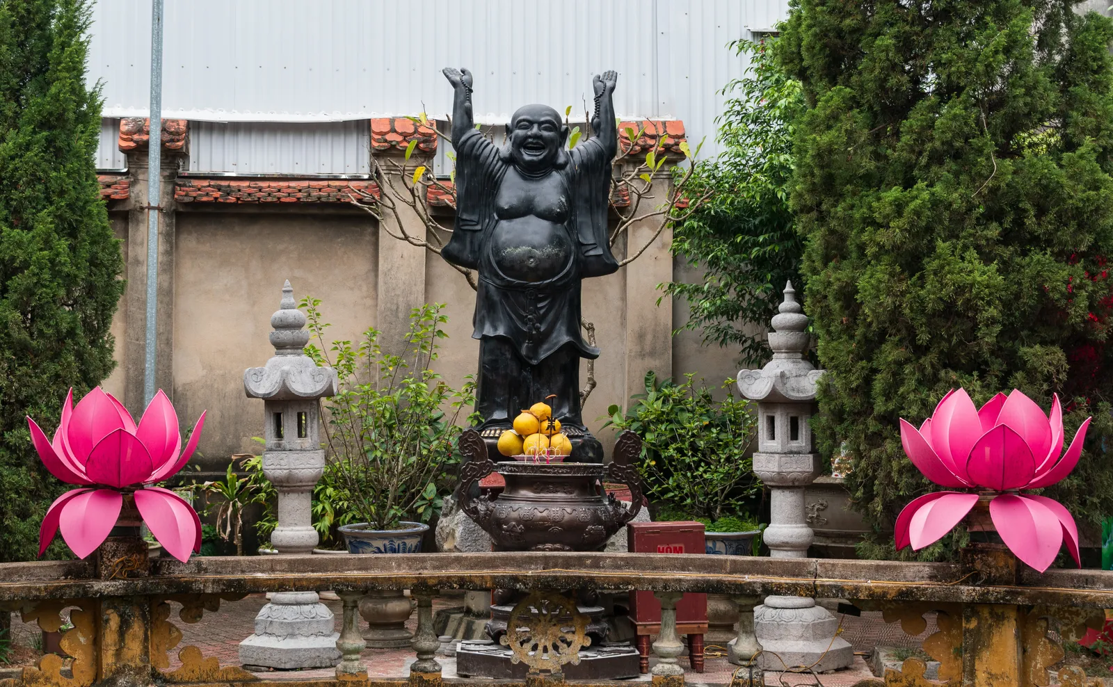 Cortile della pagoda Du Hang Statua di Budai e fiori di loto nel cortile della pagoda Du Hang ad Hai Phong