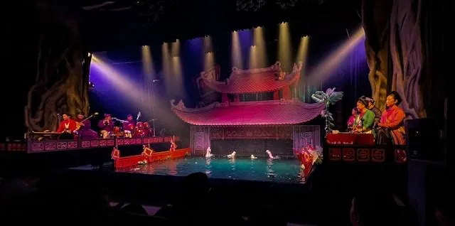 Il teatro delle marionette sull'acqua Thăng Long ad Hanoi durante lo spettacolo serale Spettacolo delle marionette sull'acqua di Hanoi al teatro Thăng Long: il palco sullo stagno, le marionette e gli orchestrali in abiti tradizionali