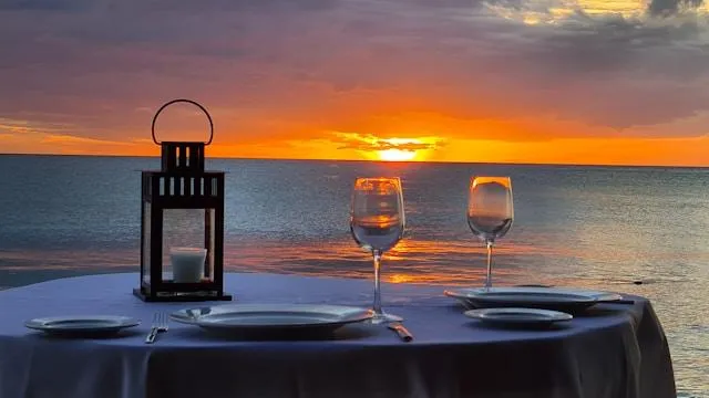 Cena romantica sulla spiaggia al tramonto Tavolo apparecchiato per una cena romantica sulla spiaggia al tramonto con calici di vino e lanterna durante una luna di miele in Vietnam