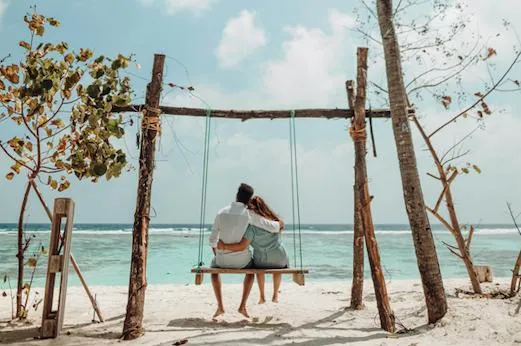 Coppia in altalena sulla spiaggia durante la luna di miele in Vietnam Coppia di sposi su un'altalena sulla spiaggia di fronte al mare, momento romantico di una luna di miele in Vietnam