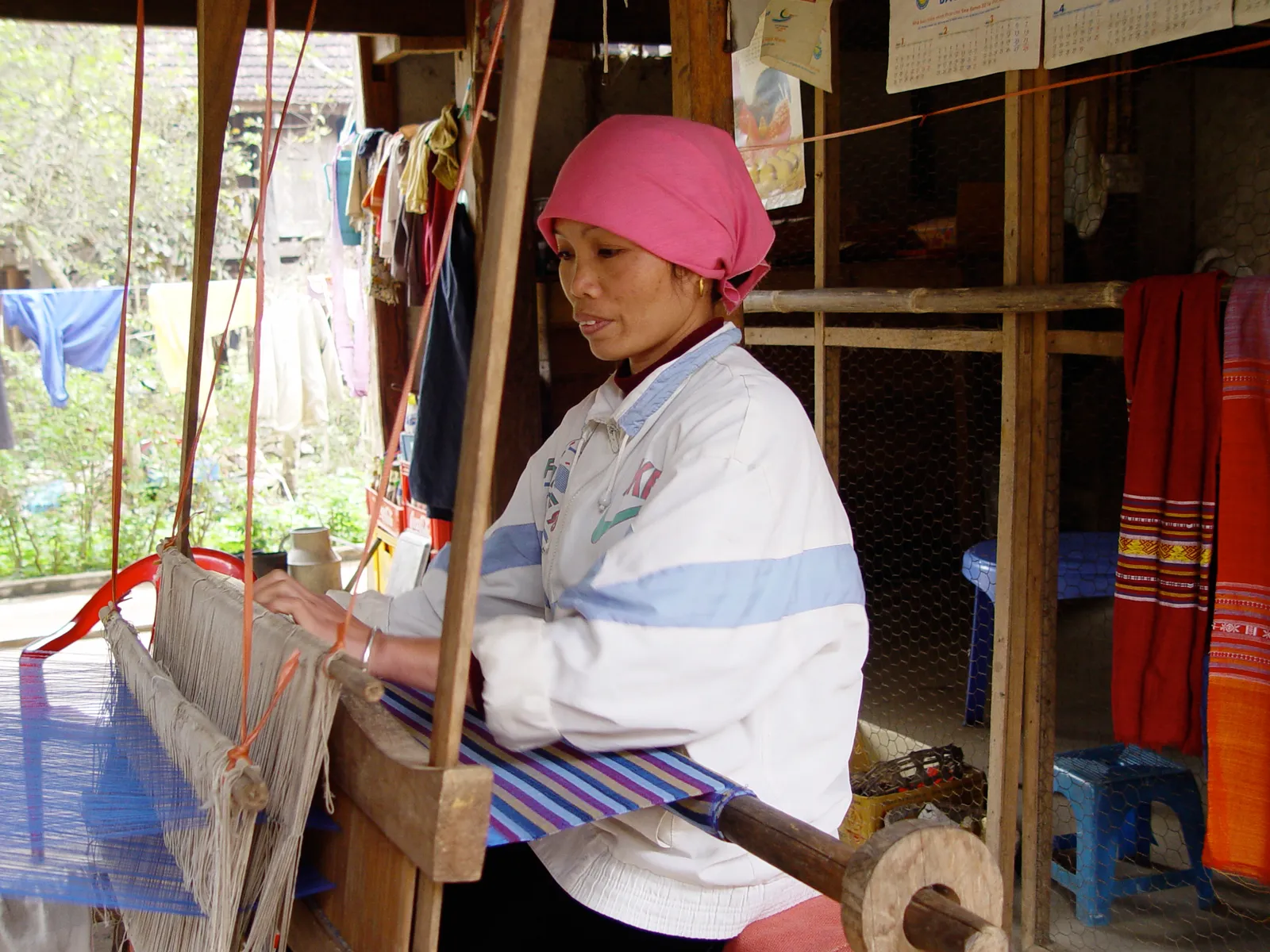 Tessitura tradizionale thai a Mai Chau Una donna thai al telaio tradizionale in un villaggio di Mai Chau