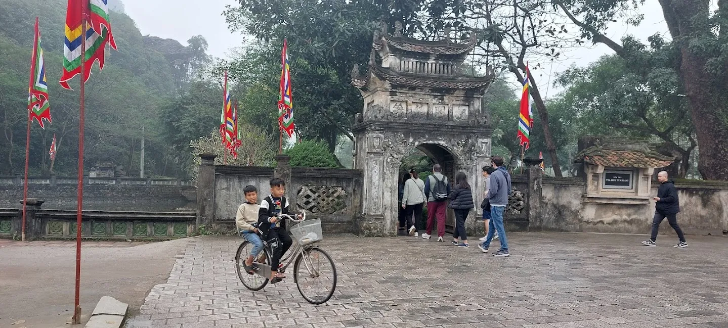 Hoa Lu, turisti attraversano un arco antico mentre due bambini girano in bicicletta