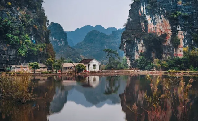 Paesaggio fluviale con rocce calcaree e abitazioni nella provincia di Ninh Binh
