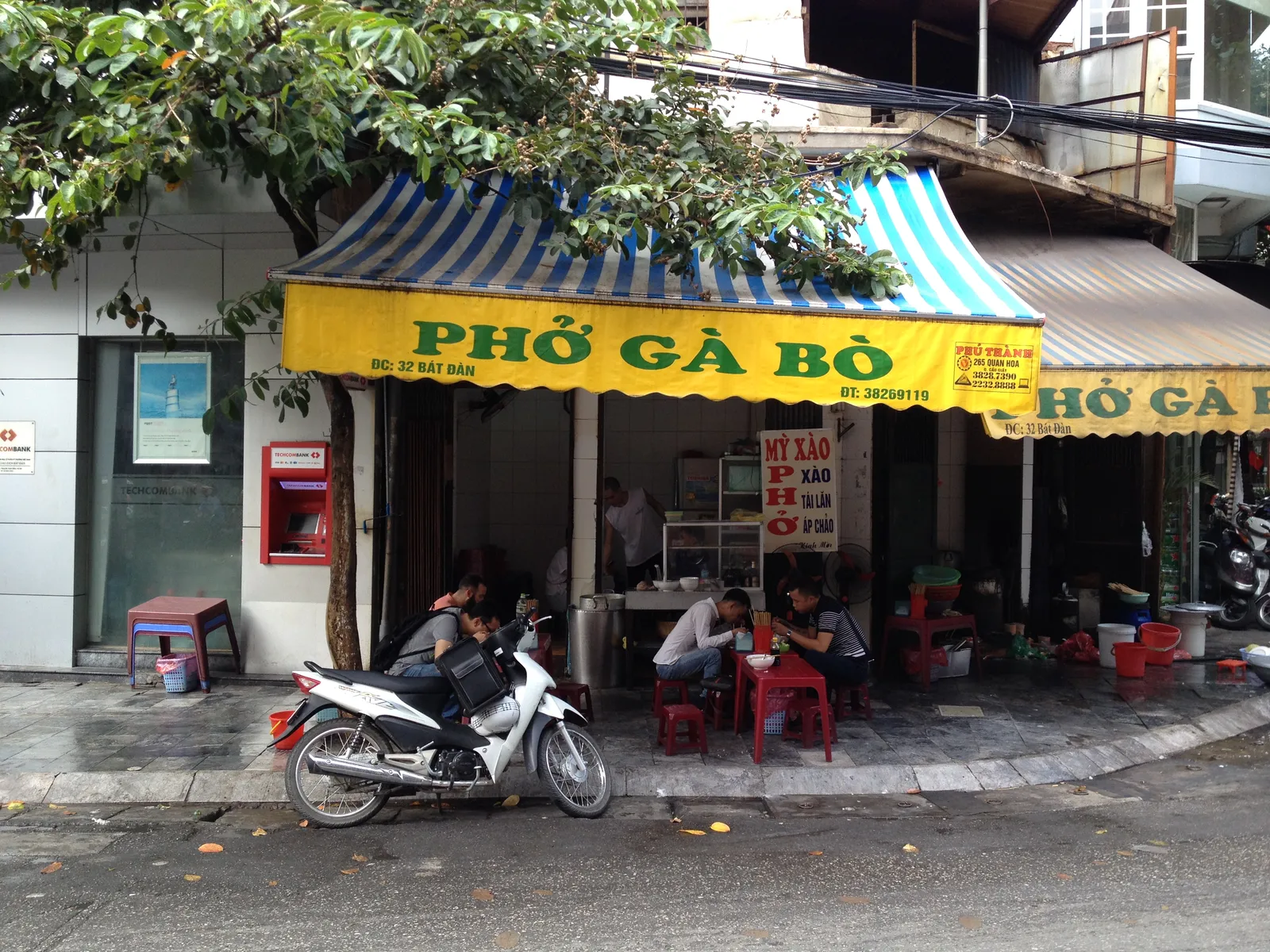 Pho di strada in via Bát Đàn, Hanoi Ristorante di strada che serve pho nel quartiere di Bát Đàn ad Hanoi, con clienti seduti sui classici sgabelli di plastica