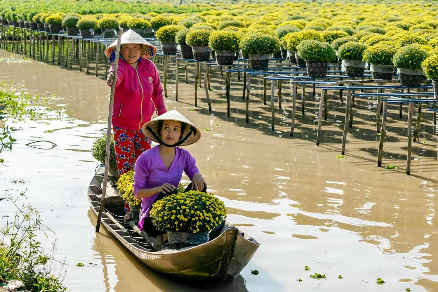 Due venditrici di frutta attraversano in barca un canale a Sa Dec
