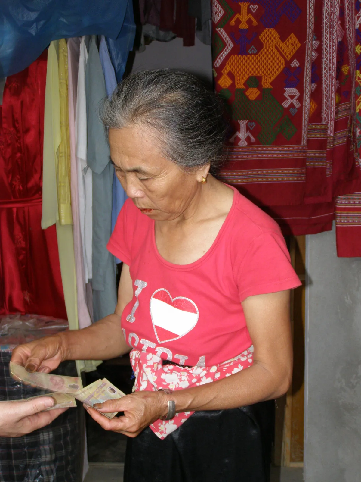 Pagamento in contanti al mercato in Vietnam Contanti in Vietnam: venditrice al mercato conta banconote in dong durante un pagamento
