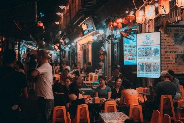 Gente che mangia per strada la sera in una via del quartiere vecchio di Hanoi, tra lanterne e tavolini di plastica