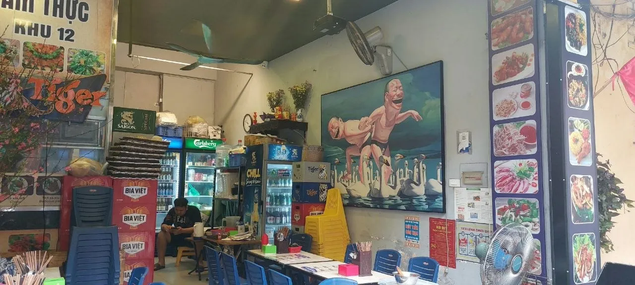 Interno di una trattoria di Hanoi con tavolini, sedie di plastica, insegne di birra vietnamita e menu con foto dei piatti