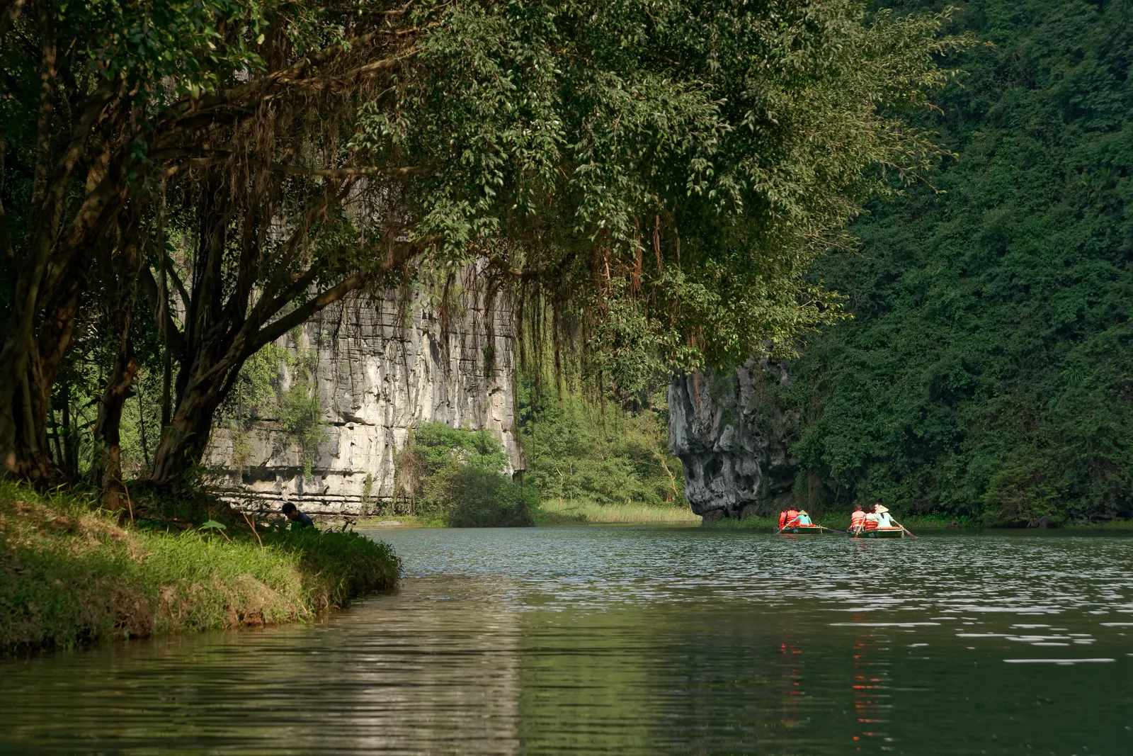 Il fiume di Trang An tra le montagne calcaree Barche turistiche sul fiume di Trang An, Ninh Binh: acque quieti tra pareti calcaree e vegetazione rigogliosa nel complesso paesaggistico UNESCO