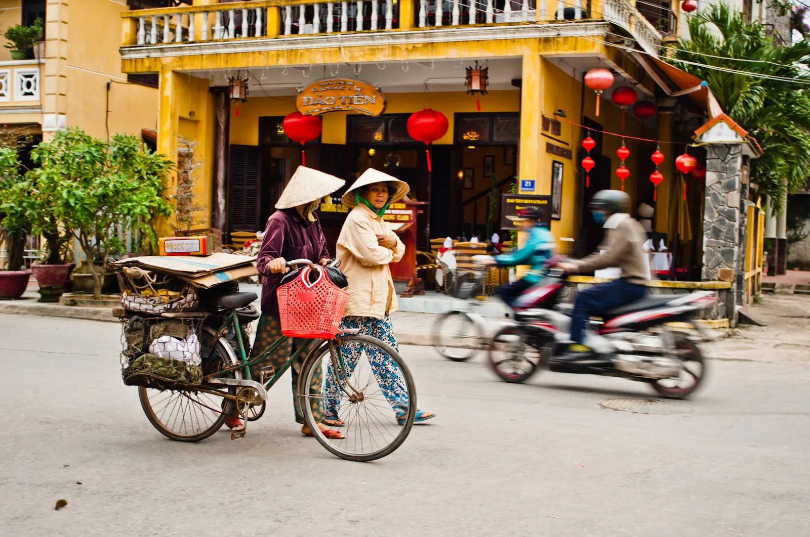 Donne che camminano con una bicicletta in una strada del centro storico di Hoi An