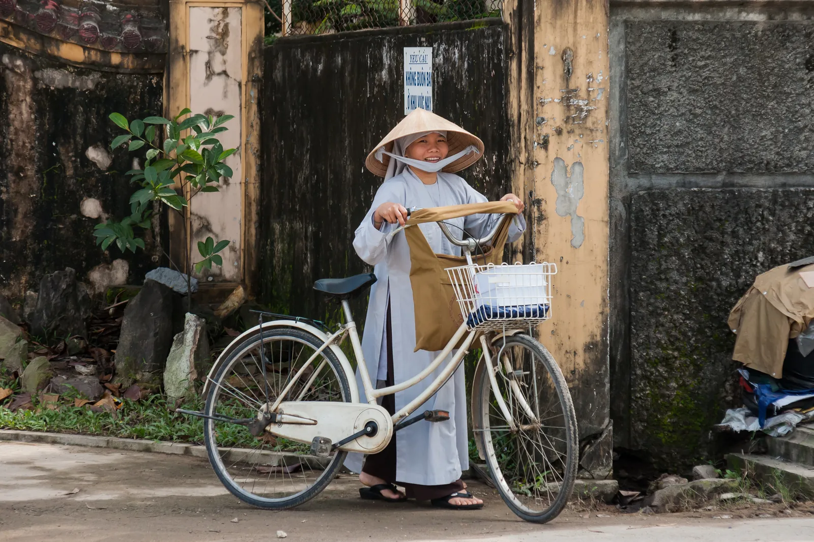 Monaca buddista con bicicletta in una strada di Hue, Vietnam